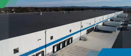 An aerial view of a large warehouse with trucks parked in front of it